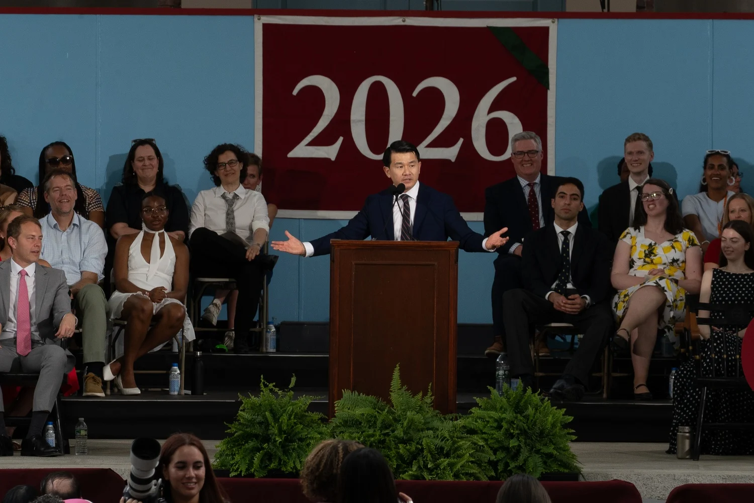 Ronny Chieng speaking at a podium during Harvard Class Day.
